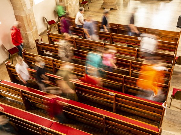 Menschen gehen durch Kirchenbänke
