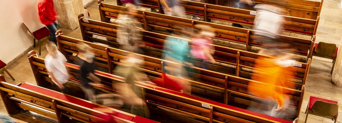 Menschen gehen durch Kirchenbänke