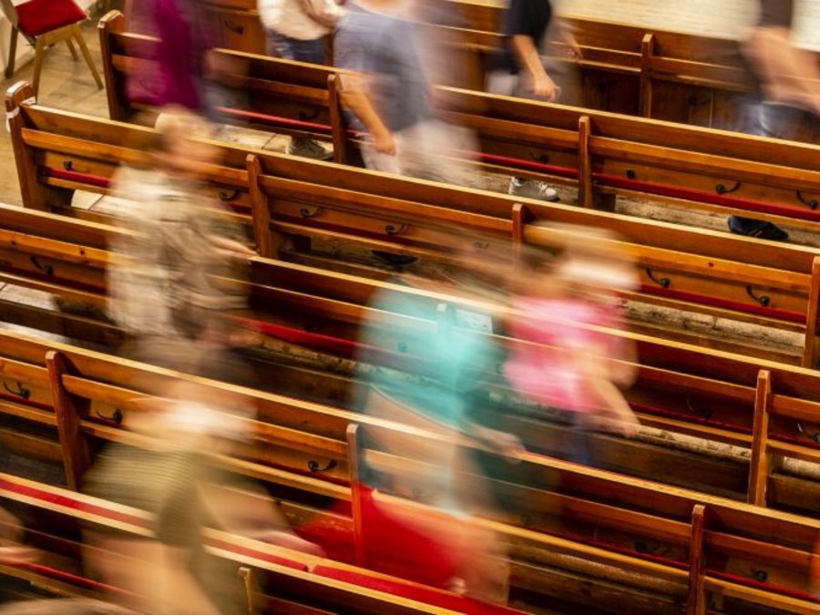 Menschen laufen durch Kirchenbänke